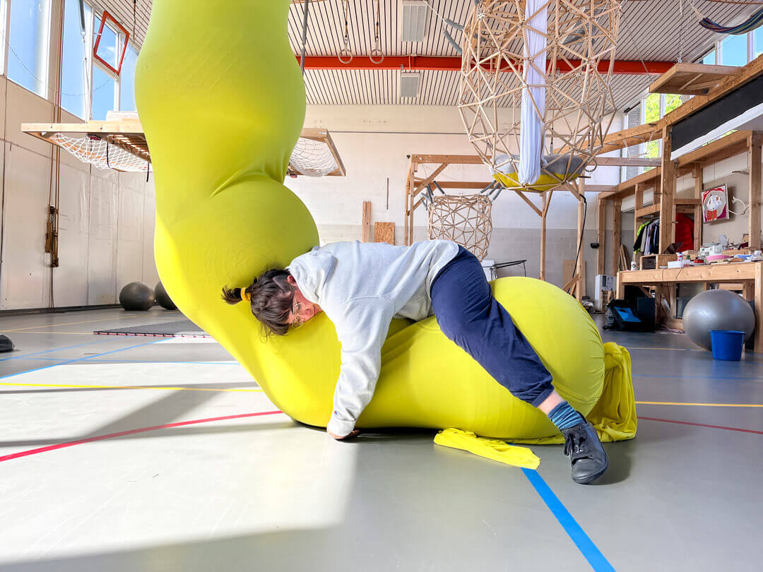 The LARVA is made from a massive sleeve of aerial silk fabric and filled with yoga balls to create a caterpillar-like structure.